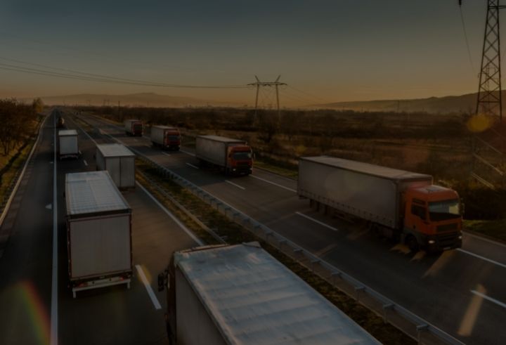 Fleet of trucks driving on the road during a sunset